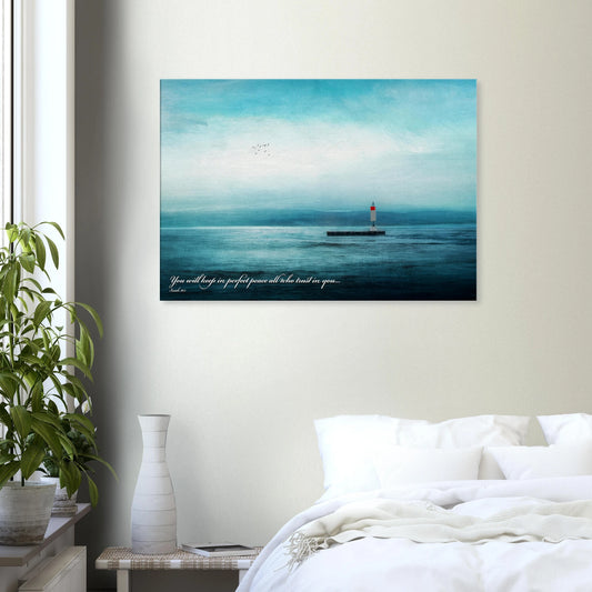 A wall art print featuring a lighthouse with a backdrop of the sea and sky, including a quote about perfect peace displayed in a bright minimalist bedroom with plant decor