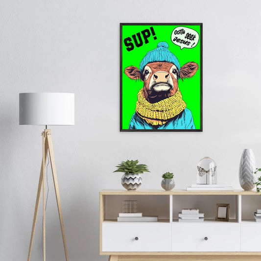 Playful Christian wall art featuring an illustrated cow wearing a blue beanie and yellow scarf on a bright green background, with SUP! and Gotta seek Jesus in a speech bubble, framed and displayed above a dresser with a floor lamp and small plants