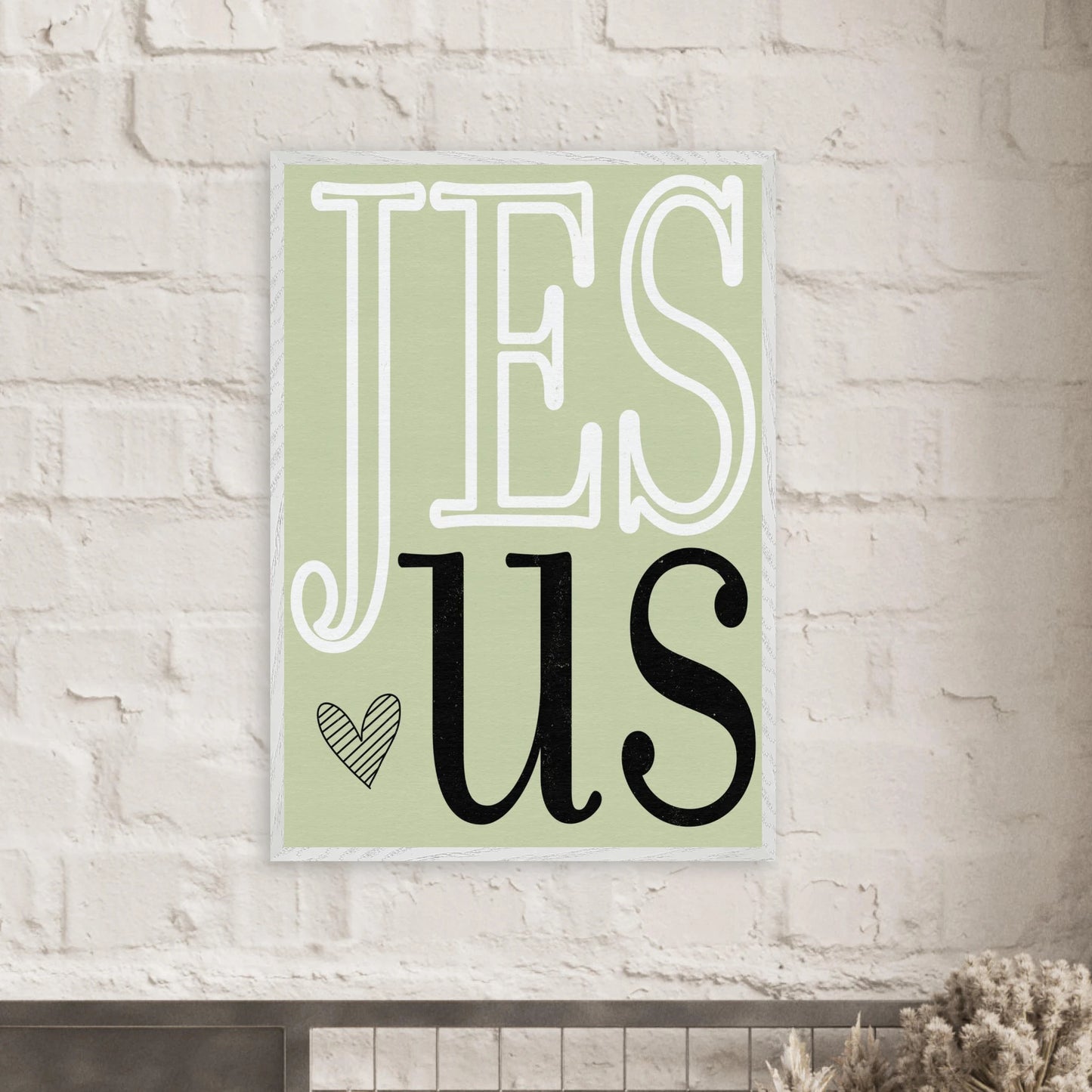Decorative sign with 'JESUS' text on a light green background, mounted on a brick wall.