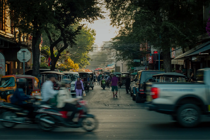 Busy street in Phnom Penh Cambodia with tuk tuks motorbikes and pedestrians during golden hour capturing daily life and movement in the city