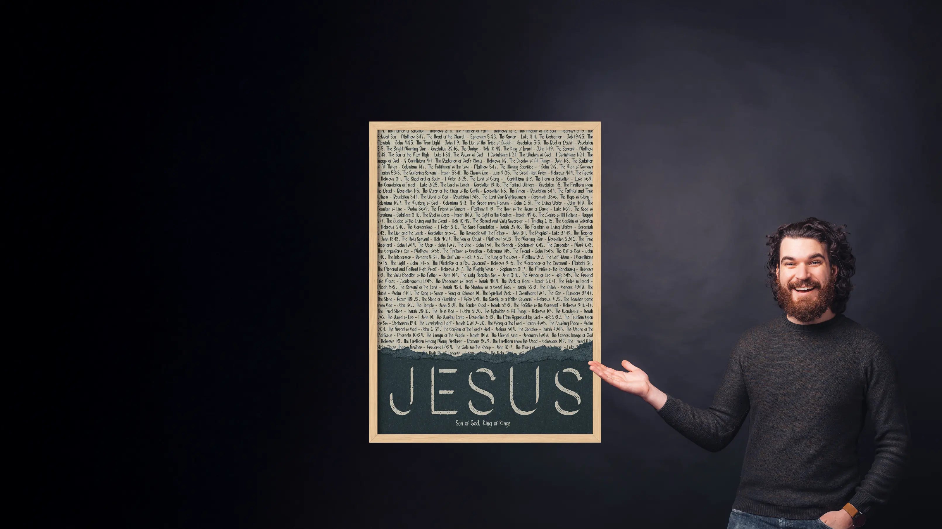 Man holding a framed text with 'JESUS' on a dark background