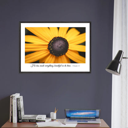 A framed art print of a close-up yellow flower with a quote from Ecclesiastes 3:11, 'He has made everything beautiful in its time.' displayed in a grey wall office
