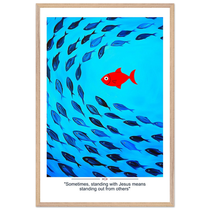 Framed Christian wall art featuring a red fish swimming in water with blue fish, and the text 'Sometimes standing with Jesus means standing out from others' as a quote.