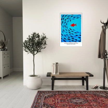 Christian wall art showing a red fish swimming against a school of blue fish with the message Sometimes standing with Jesus means standing out displayed in a minimalist entryway with bench, plant, and coat rack