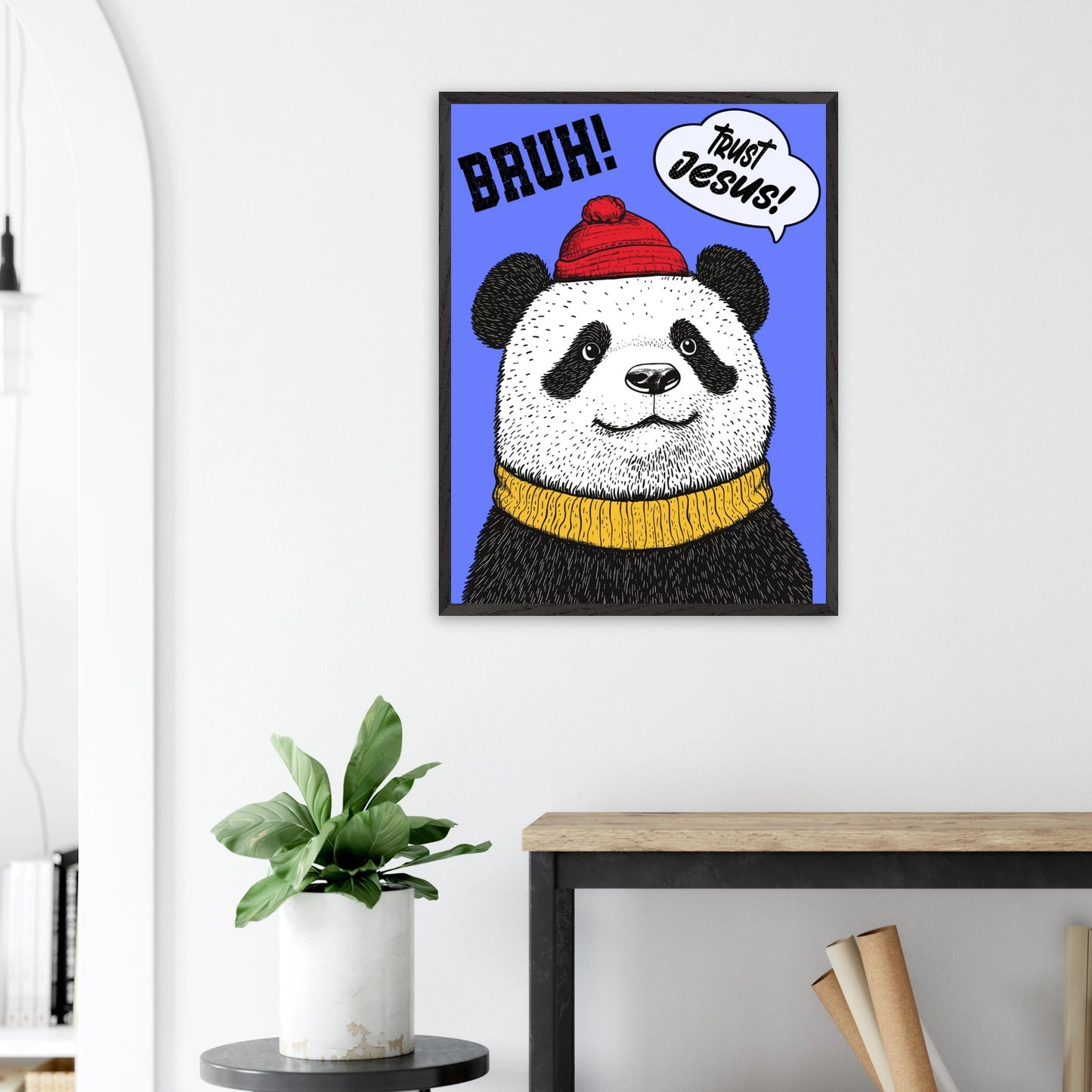 Playful Christian wall art illustration of a panda wearing a red beanie and yellow sweater on a blue background with the words BRUH and Trust Jesus in speech bubbles displayed above a plant on a side table in a bright modern living room