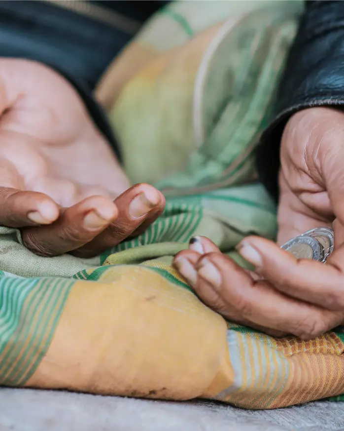 Close-up of two pairs of hands holding a coin over a patterned fabric background