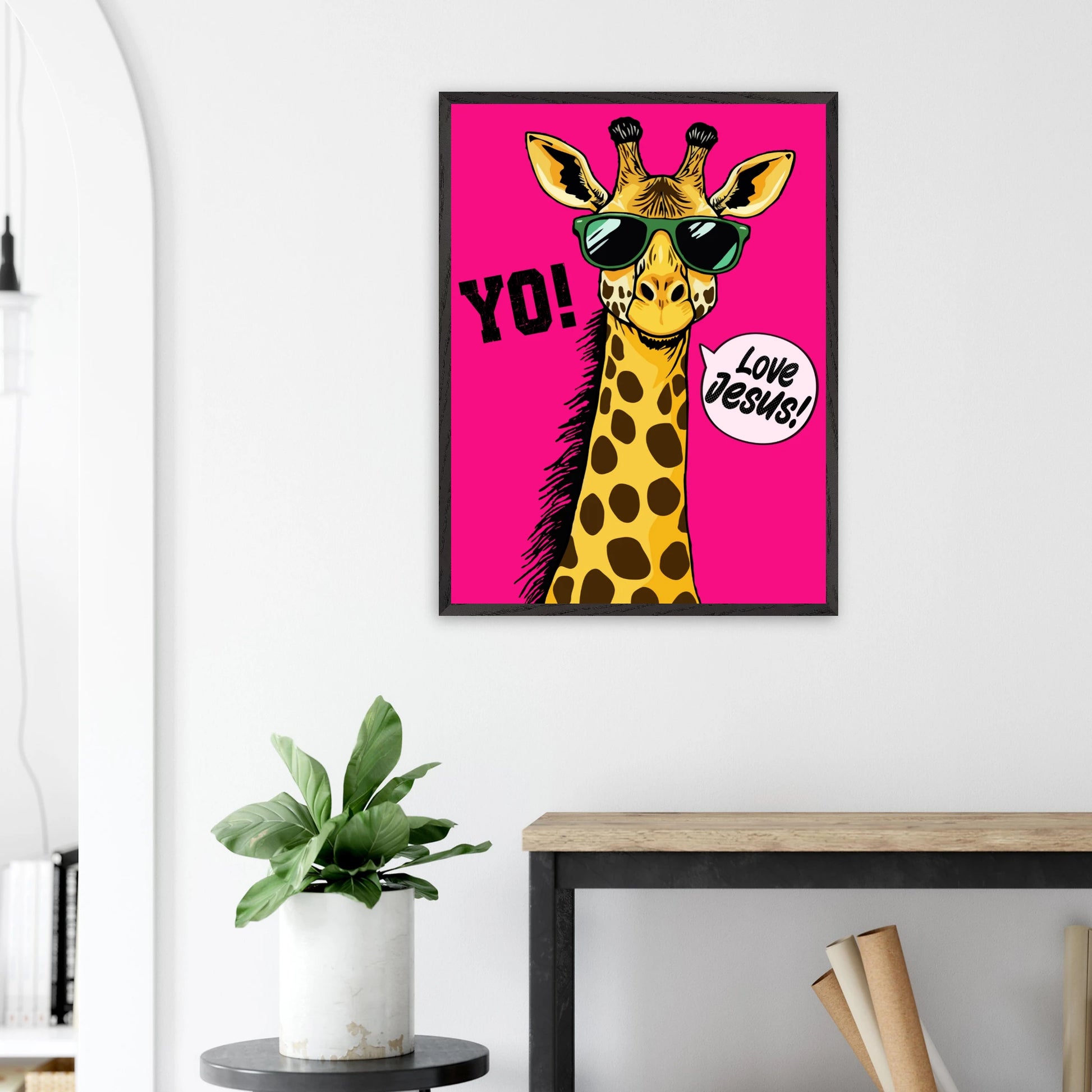 Christian wall art featuring a playful giraffe wearing sunglasses on a bright pink background with the message Love Jesus displayed in a bright modern room with plant decor