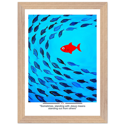 Framed Christian wall art featuring a red fish swimming in water with blue fish, and the text 'Sometimes standing with Jesus means standing out from others' as a quote.