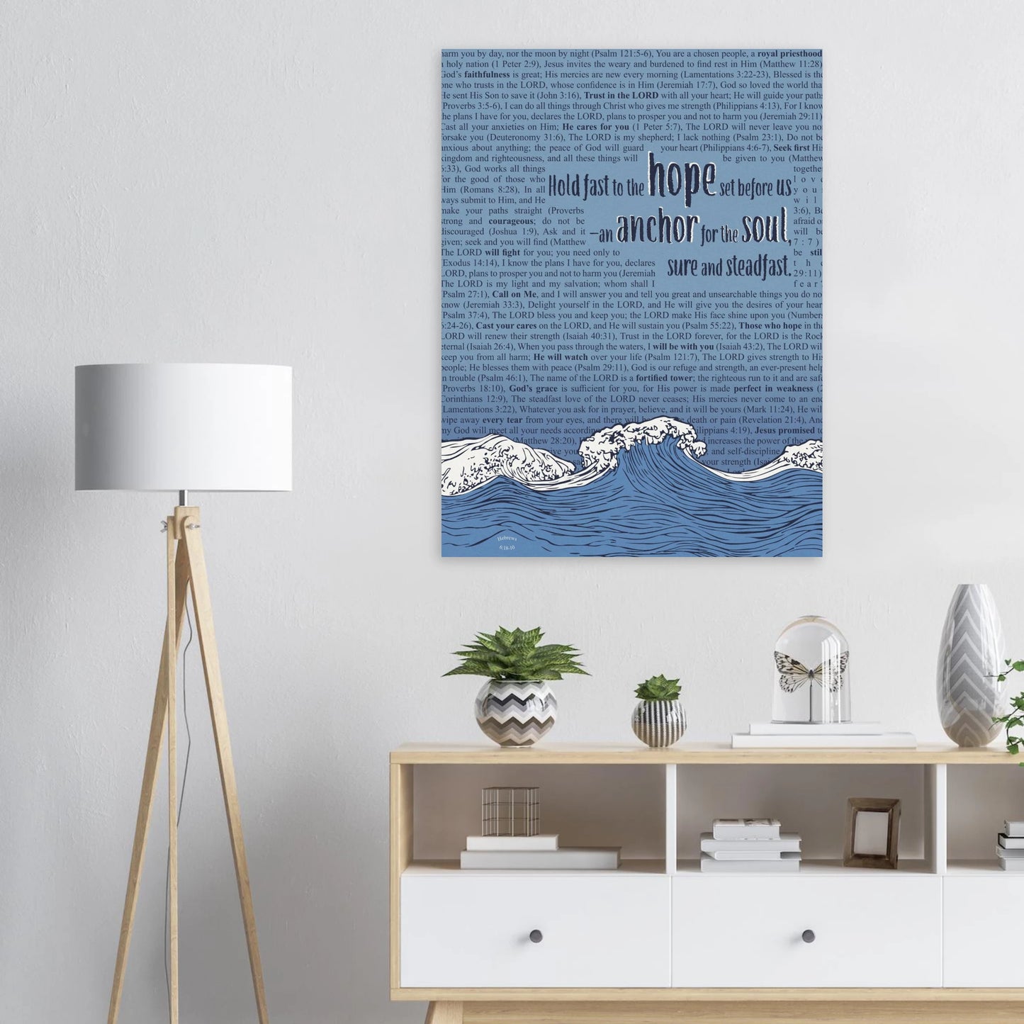 Christian canvas artwork featuring waves and Hebrews 6:19 above a white dresser with plants