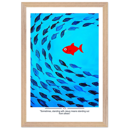 Framed Christian wall art featuring a red fish swimming in water with blue fish, and the text 'Sometimes standing with Jesus means standing out from others' as a quote.