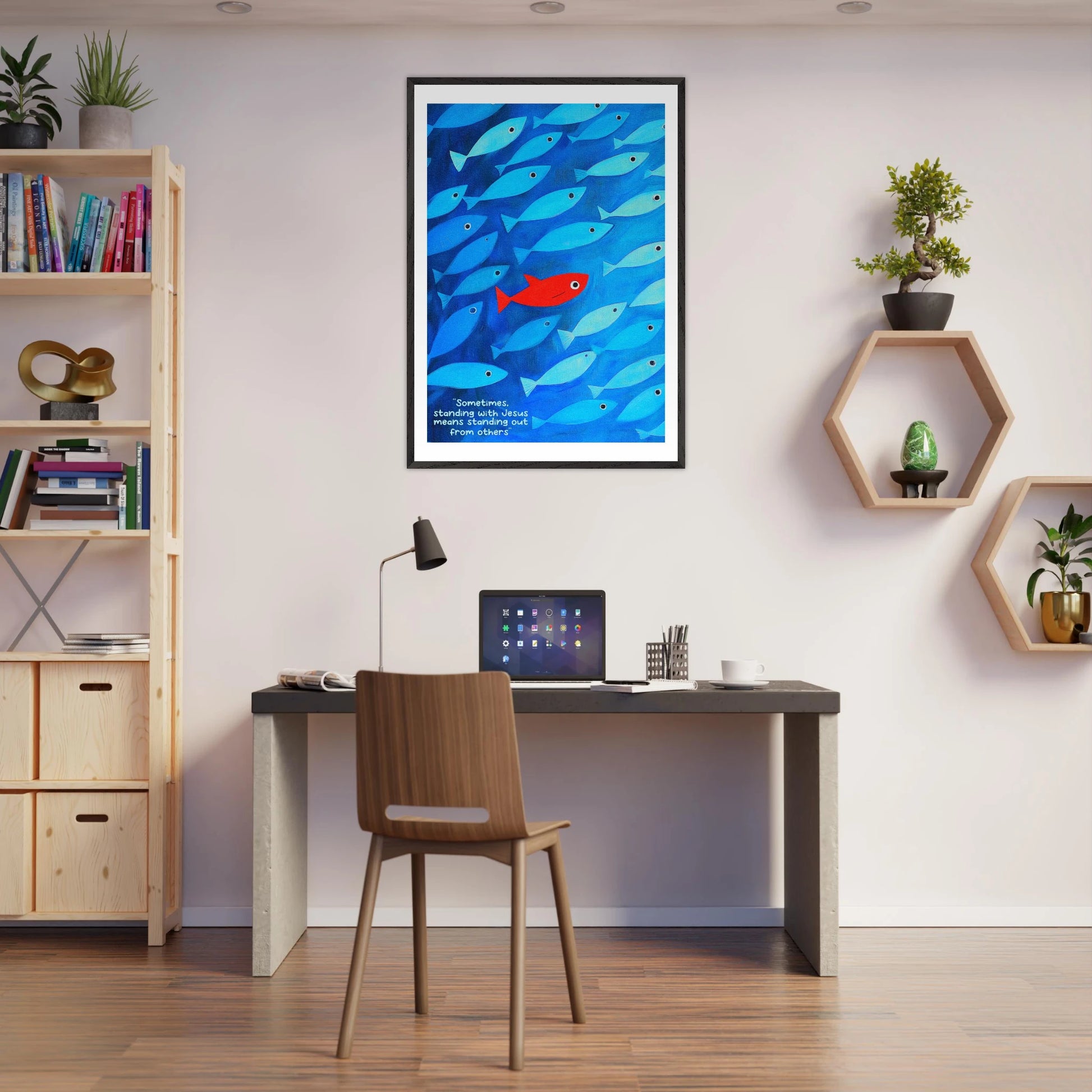 Framed wall art featuring a school of blue fish with a single red fish, and text that reads: 'Sometimes standing with Jesus means standing out from others.' displayed in a modern minimalist office