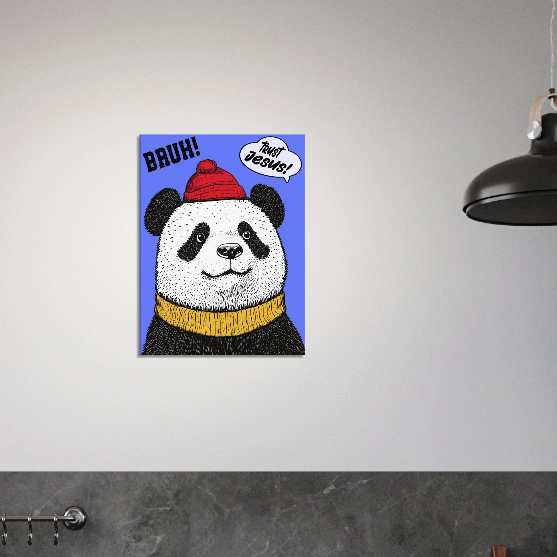 A canvas wall art featuring a cartoon illustration of a panda with a red beanie hat, a yellow scarf, and a speech bubble saying 'Trust Jesus' with a blue background displayed in a bright minimalist black and white kitchen