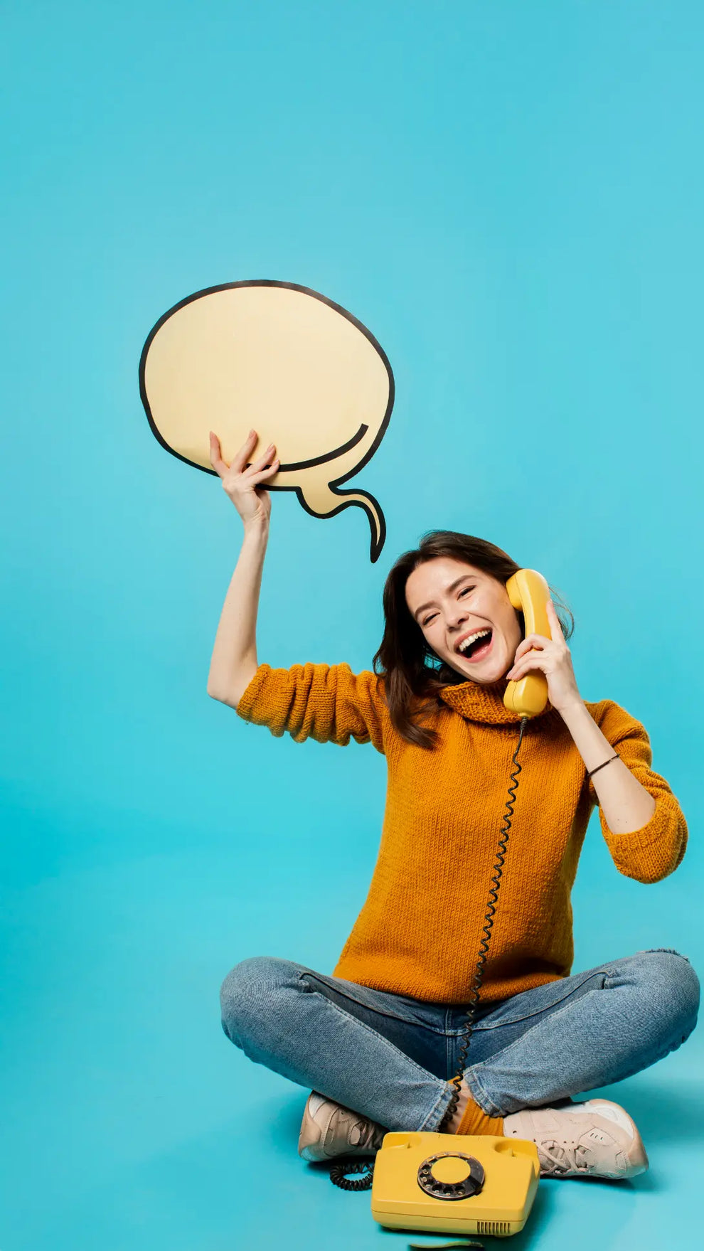 Person sitting on the floor with a yellow phone and speech bubble against a blue background