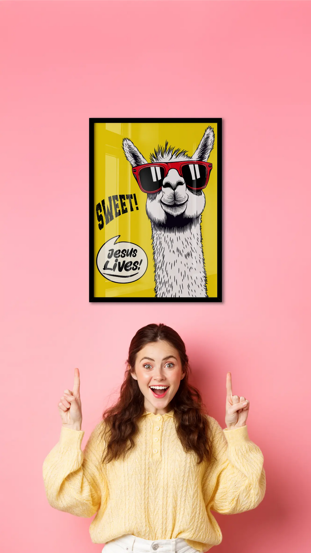 Framed poster of a llama with sunglasses on a pink wall, with a person in a yellow sweater pointing at it.