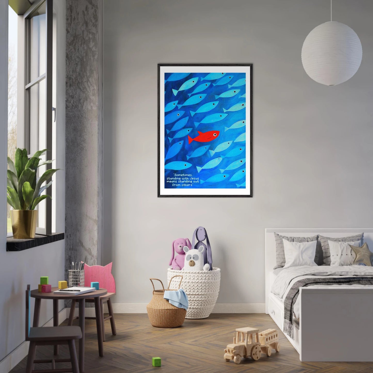 Framed wall art featuring a school of blue fish with a single red fish, and text that reads: 'Sometimes standing with Jesus means standing out from others.'  displayed in a cozy nursery bedroom interior