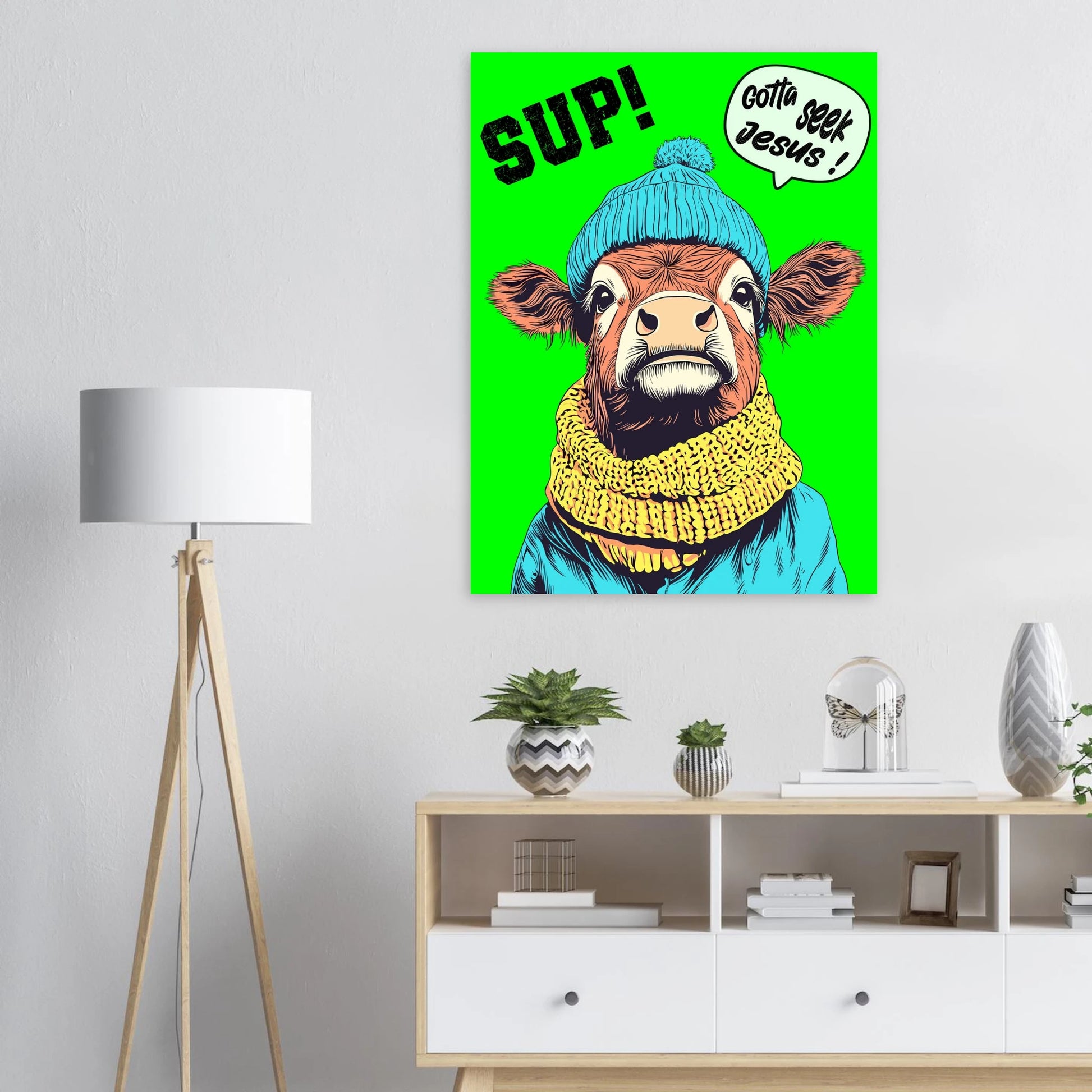 Colorful poster of a cow wearing a blue beanie and yellow scarf with text on a green background, displayed in a room.