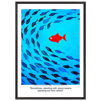 Framed Christian wall art featuring a red fish swimming in water with blue fish, and the text 'Sometimes standing with Jesus means standing out from others' as a quote.