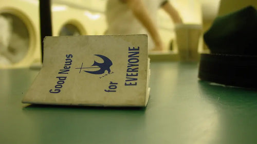 Small book titled 'Good News for Everyone' on a green surface with a blurred background