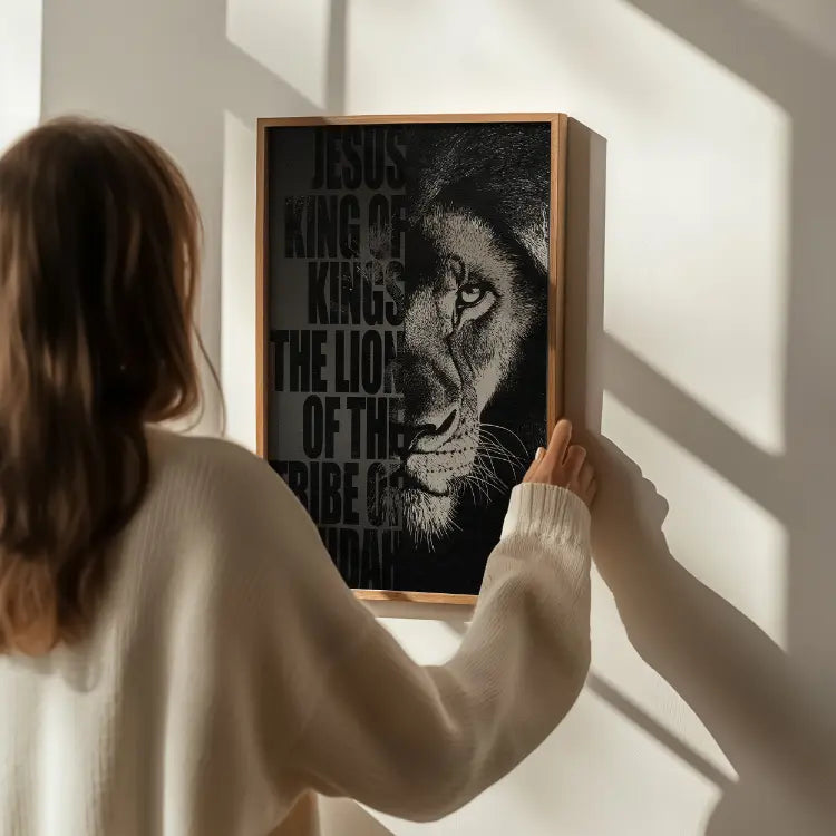 Person hanging a framed picture of a lion with text on a wall