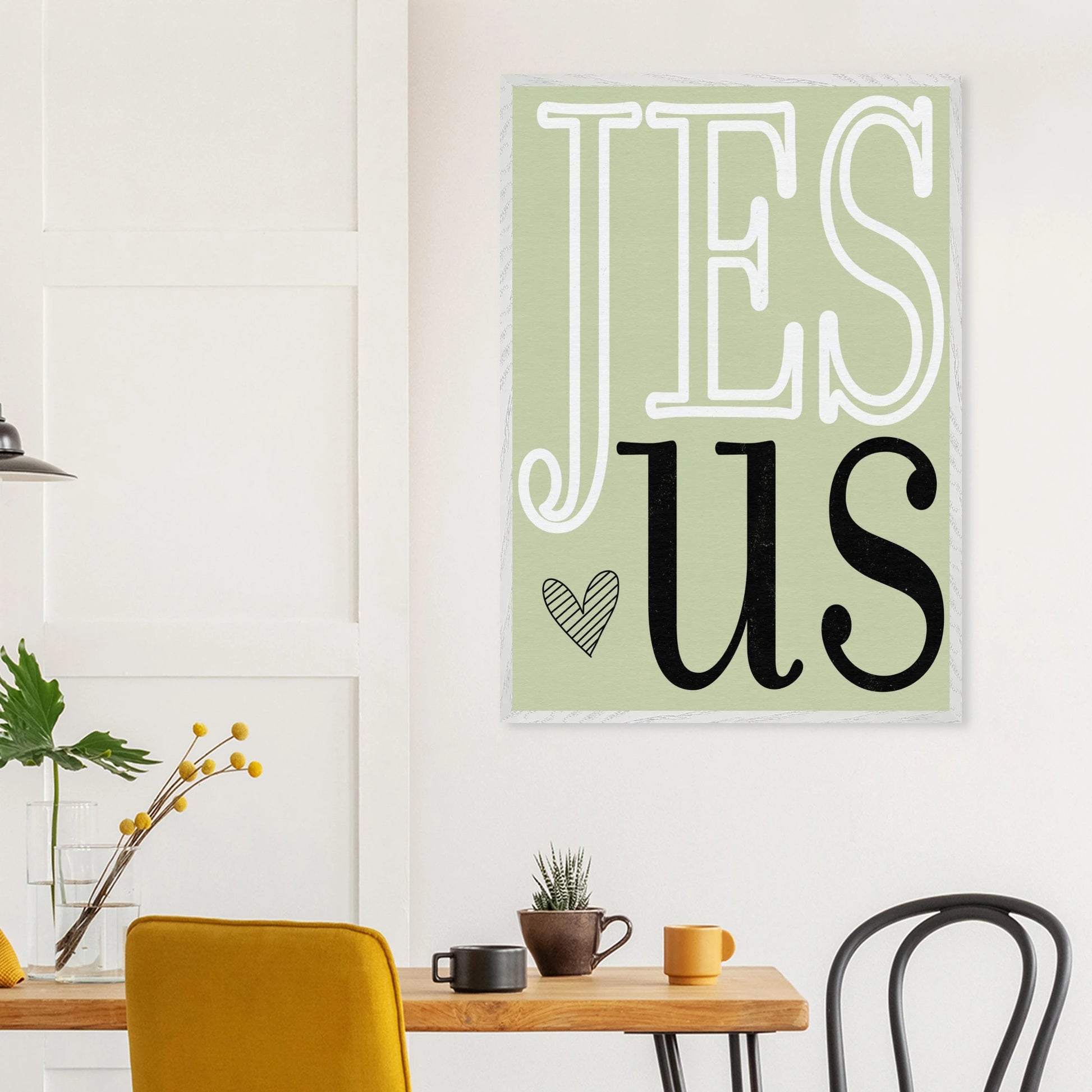 Poster with 'JESUS' on a wall above a table with decor items.