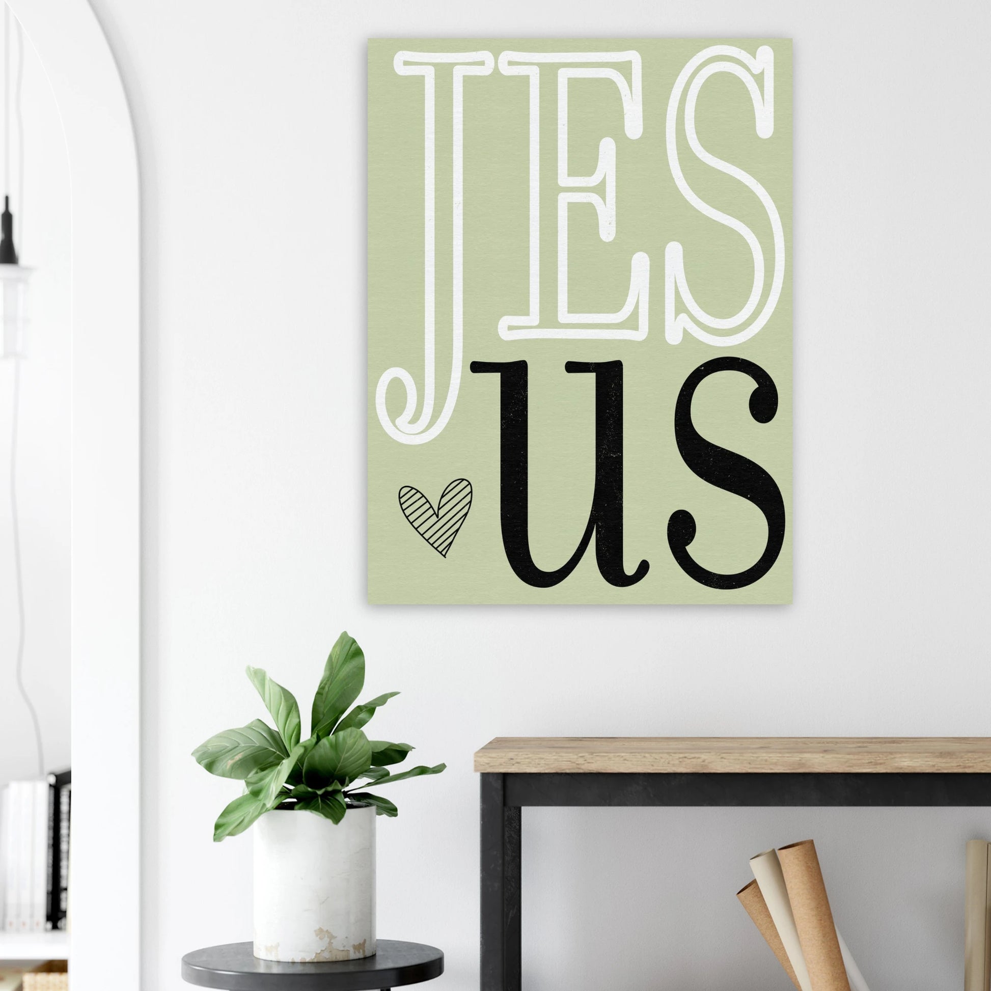 Decorative wall art with 'Jesus' on a light green background in a room setting.