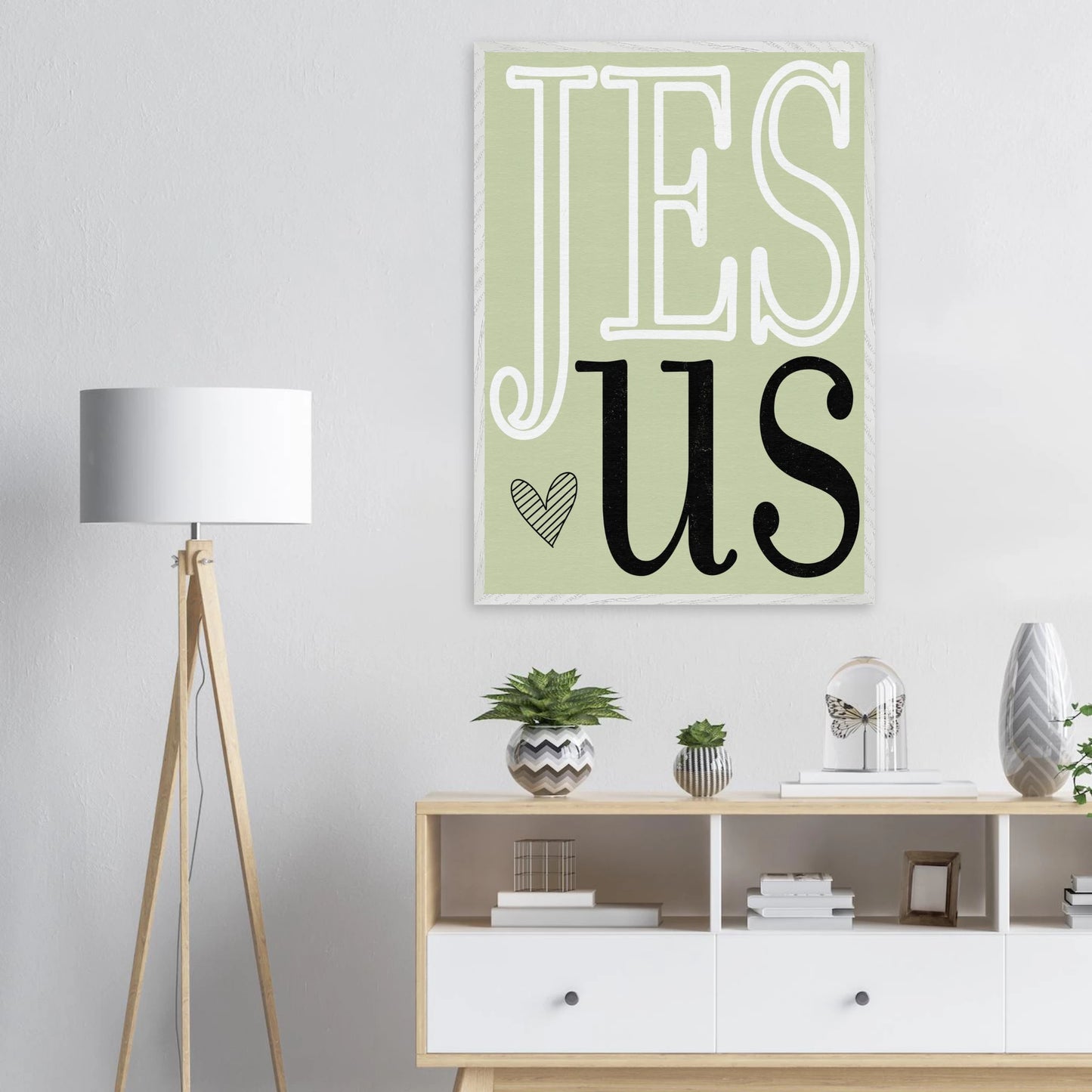 Decorative wall art with 'JESUS' on a light green background in a living room setting.