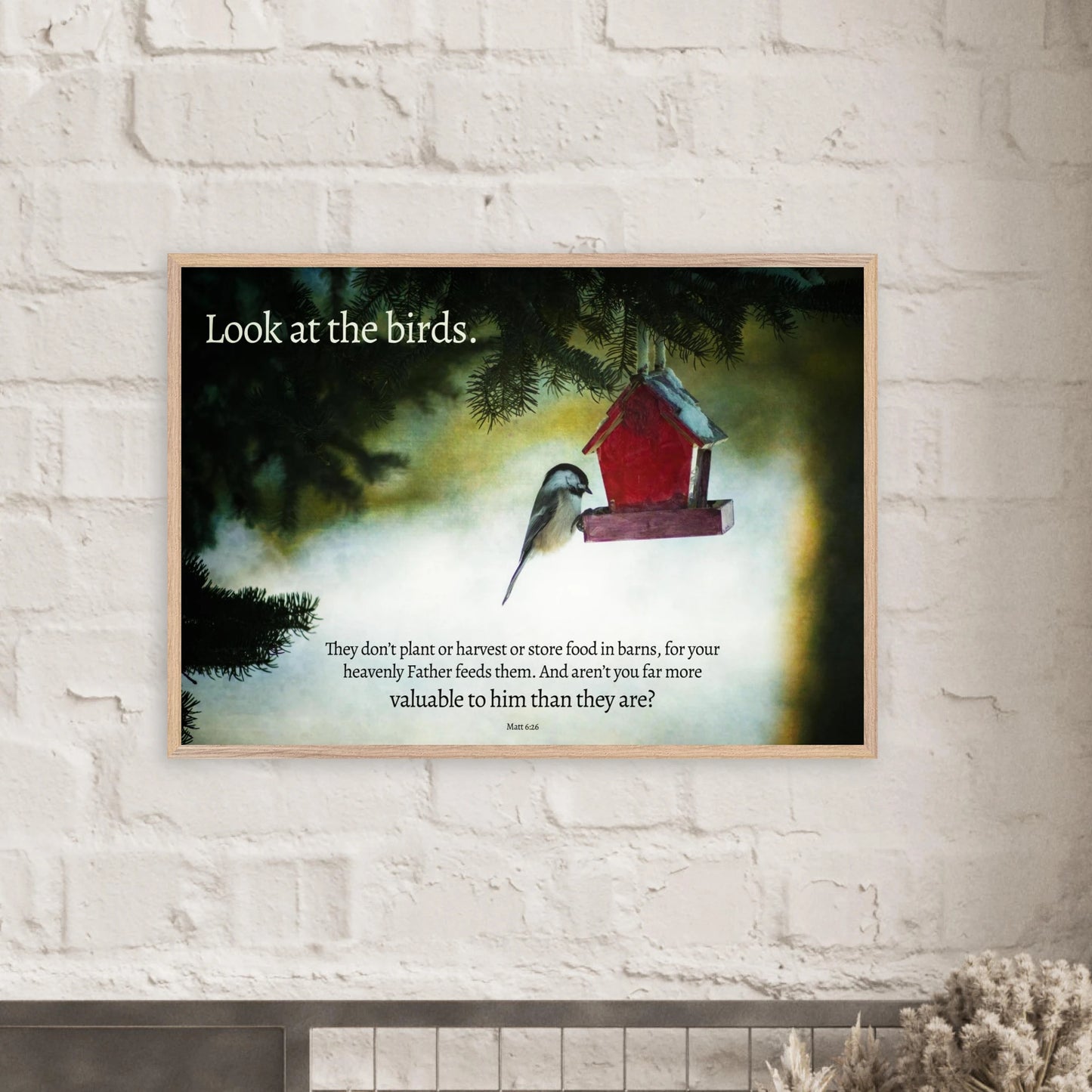 Framed artwork with a bird and red birdhouse on a white brick wall.