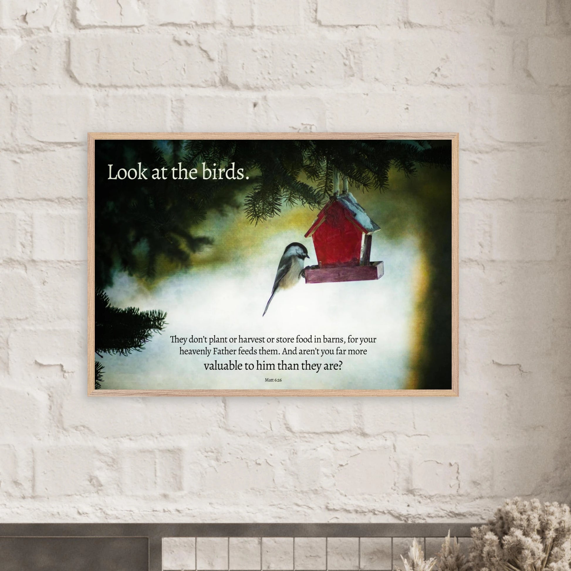 Framed artwork with a bird and red birdhouse on a white brick wall.