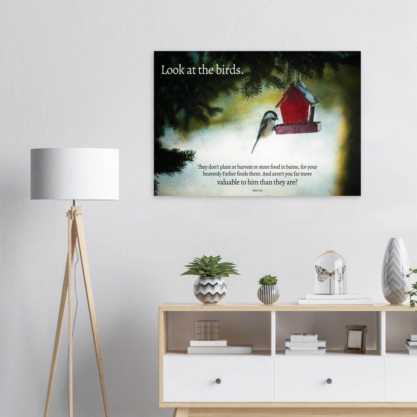 Framed artwork with a bird and birdhouse on a wall above a shelf with decor items.