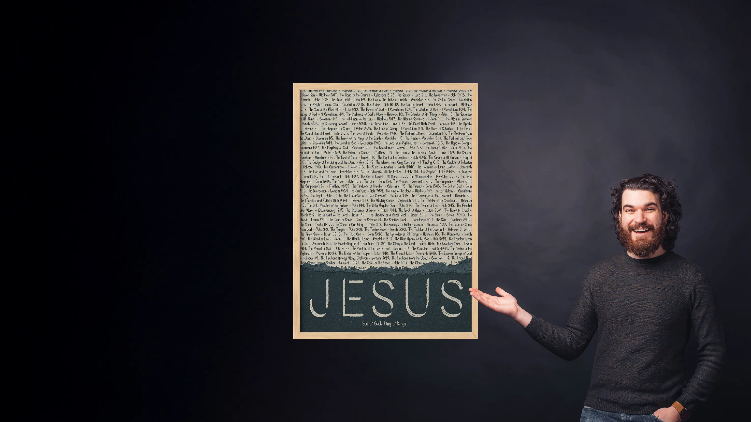 Man holding a framed text poster with 'Jesus' on a dark background