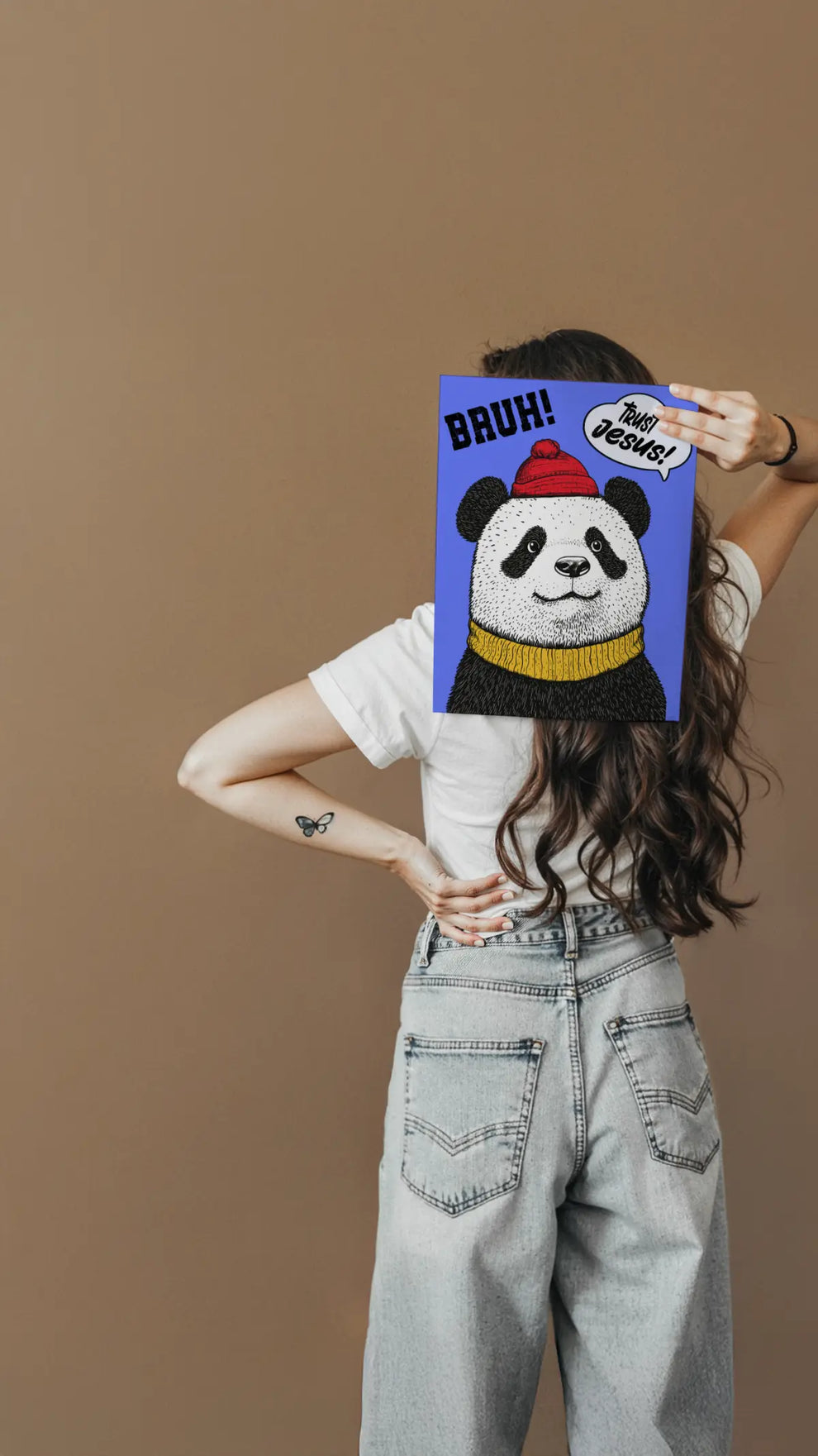 Person holding a colorful panda mask with text against a brown background