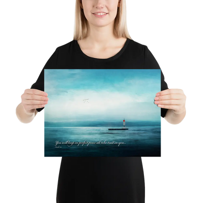 Person holding a poster with a lighthouse and ocean scene