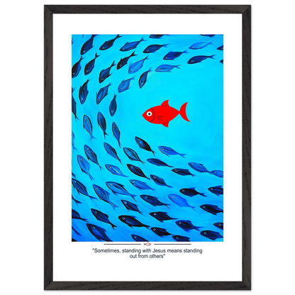 Framed Christian wall art featuring a red fish swimming in water with blue fish, and the text 'Sometimes standing with Jesus means standing out from others' as a quote.