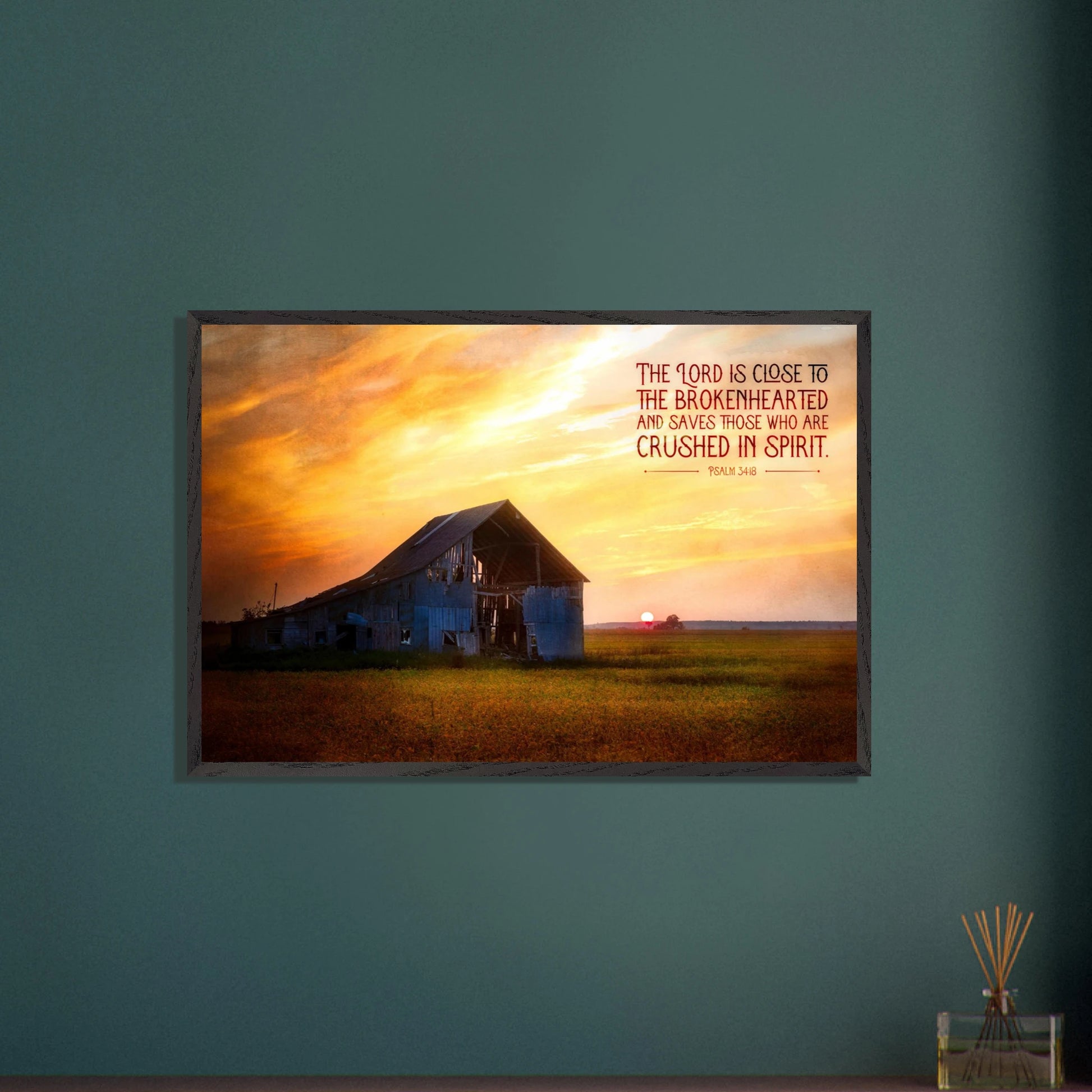 Framed artwork of a barn with a sunset and inspirational quote on a teal wall.