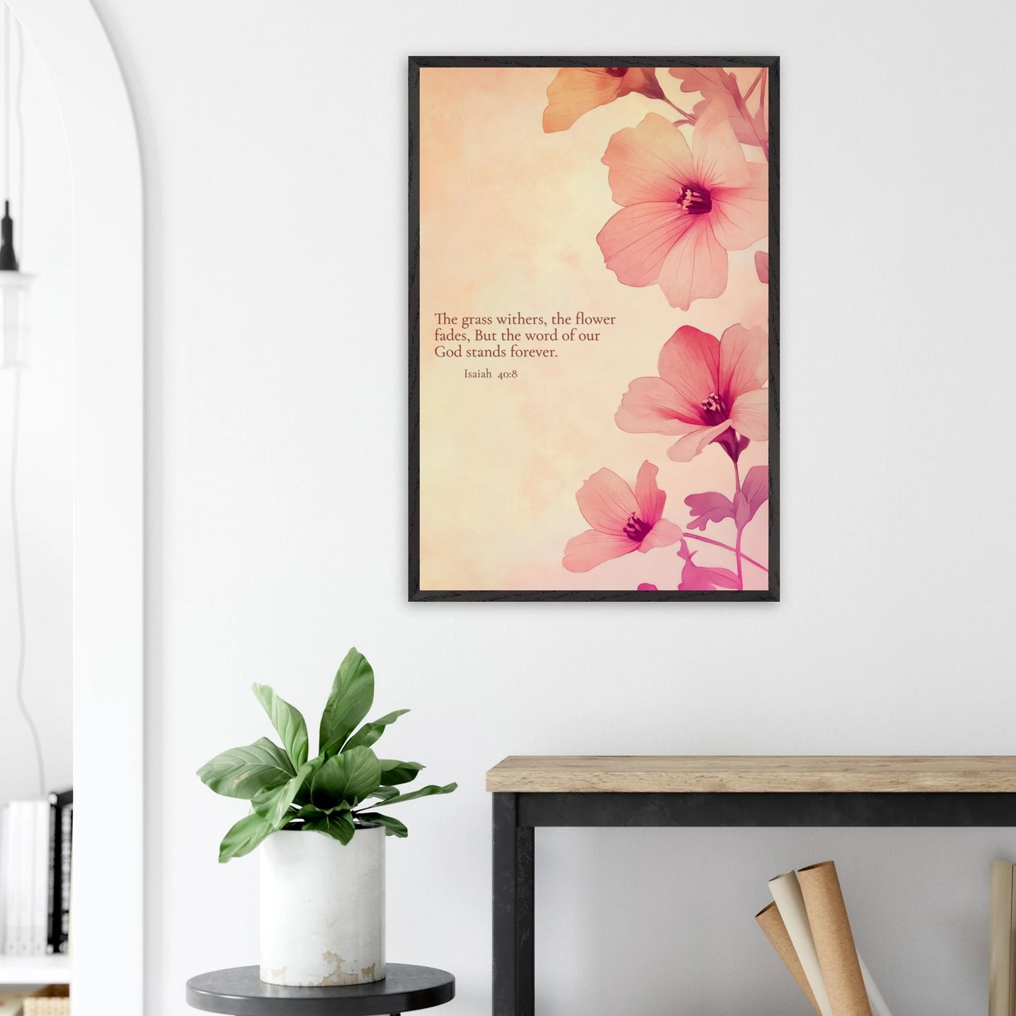 Framed Christian wall art with pink flowers and Isaiah 40:8 displayed above a plant on a side table in a bright modern living room.
