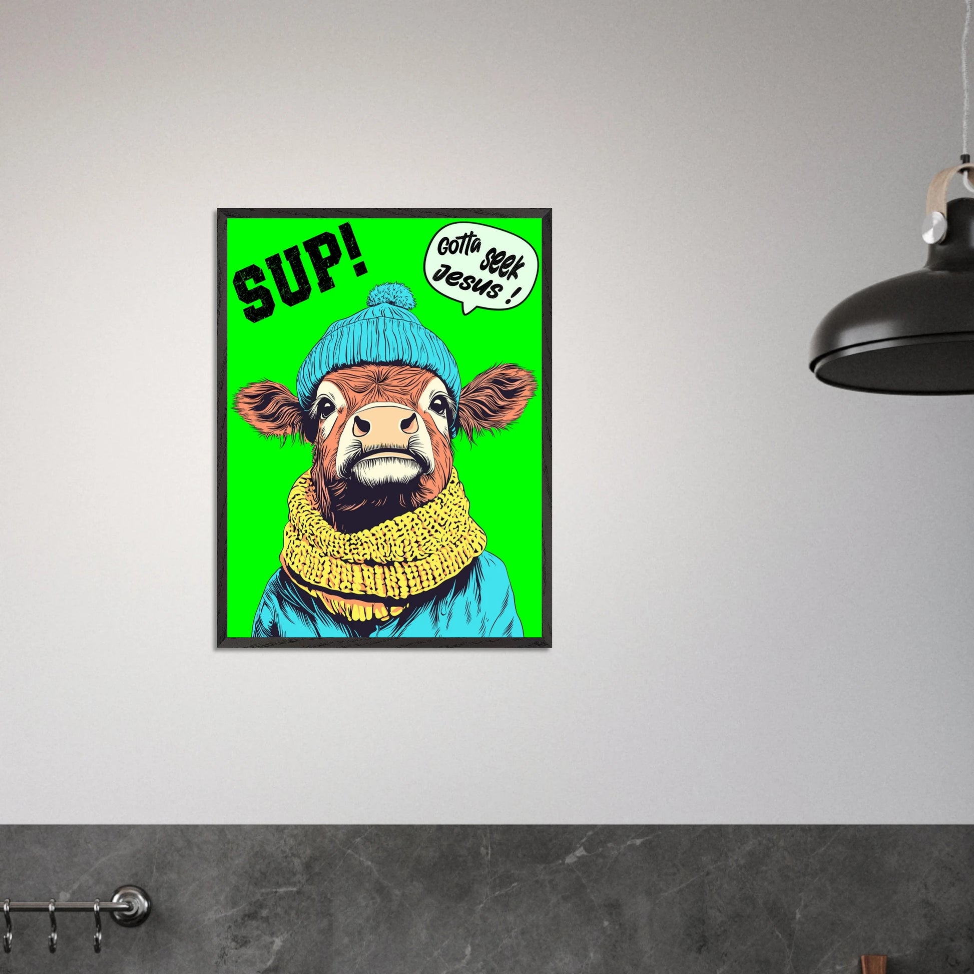 Playful Christian wall art featuring an illustrated cow wearing a blue beanie and yellow scarf on a bright green background, with SUP! and Gotta seek Jesus in a speech bubble, framed and displayed as a framed print in a modern minimalist interior
