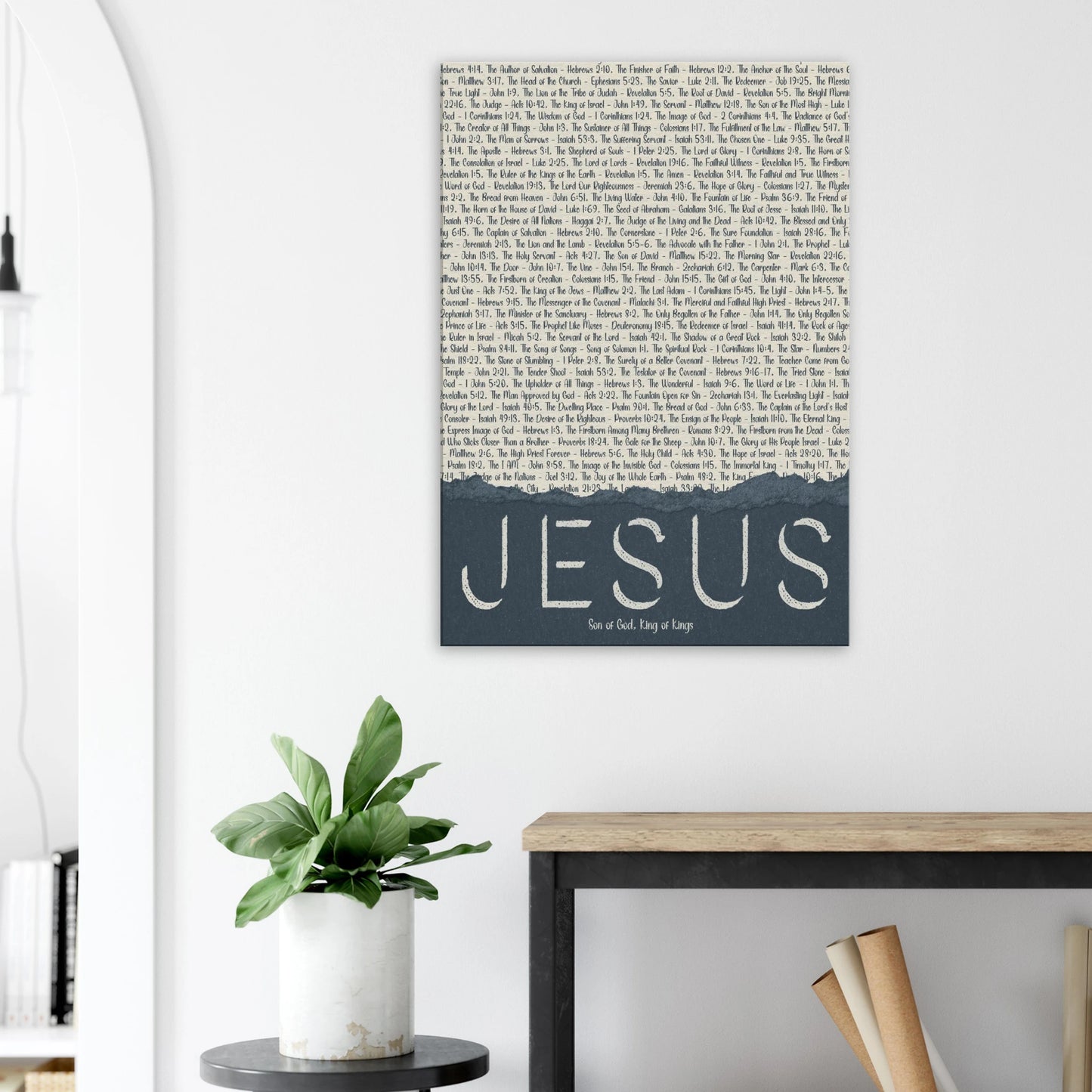 Wall art with 'Jesus' on a white wall above a desk and plant