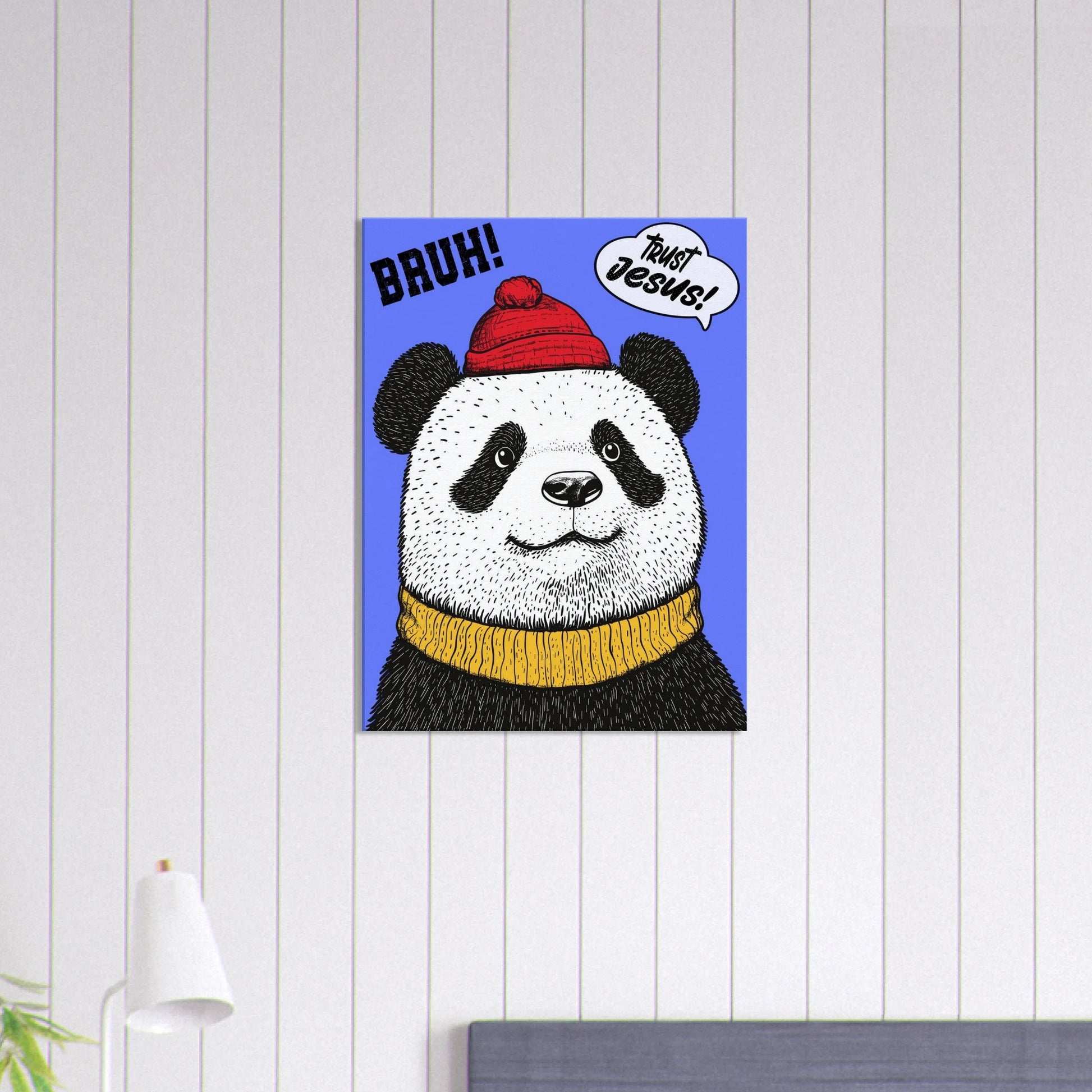 A canvas wall art featuring a cartoon illustration of a panda with a red beanie hat, a yellow scarf, and a speech bubble saying 'Trust Jesus' with a blue background displayed in a bright minimalist room with a small lamp decor.