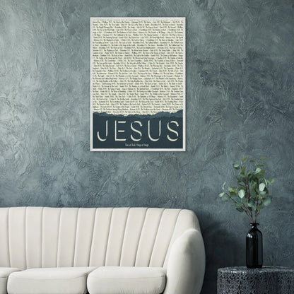 A framed wall art print with the word 'JESUS' in bold lettering, followed by a list of names and scriptures related to Jesus, against a white background hanging over a white couch in a living room