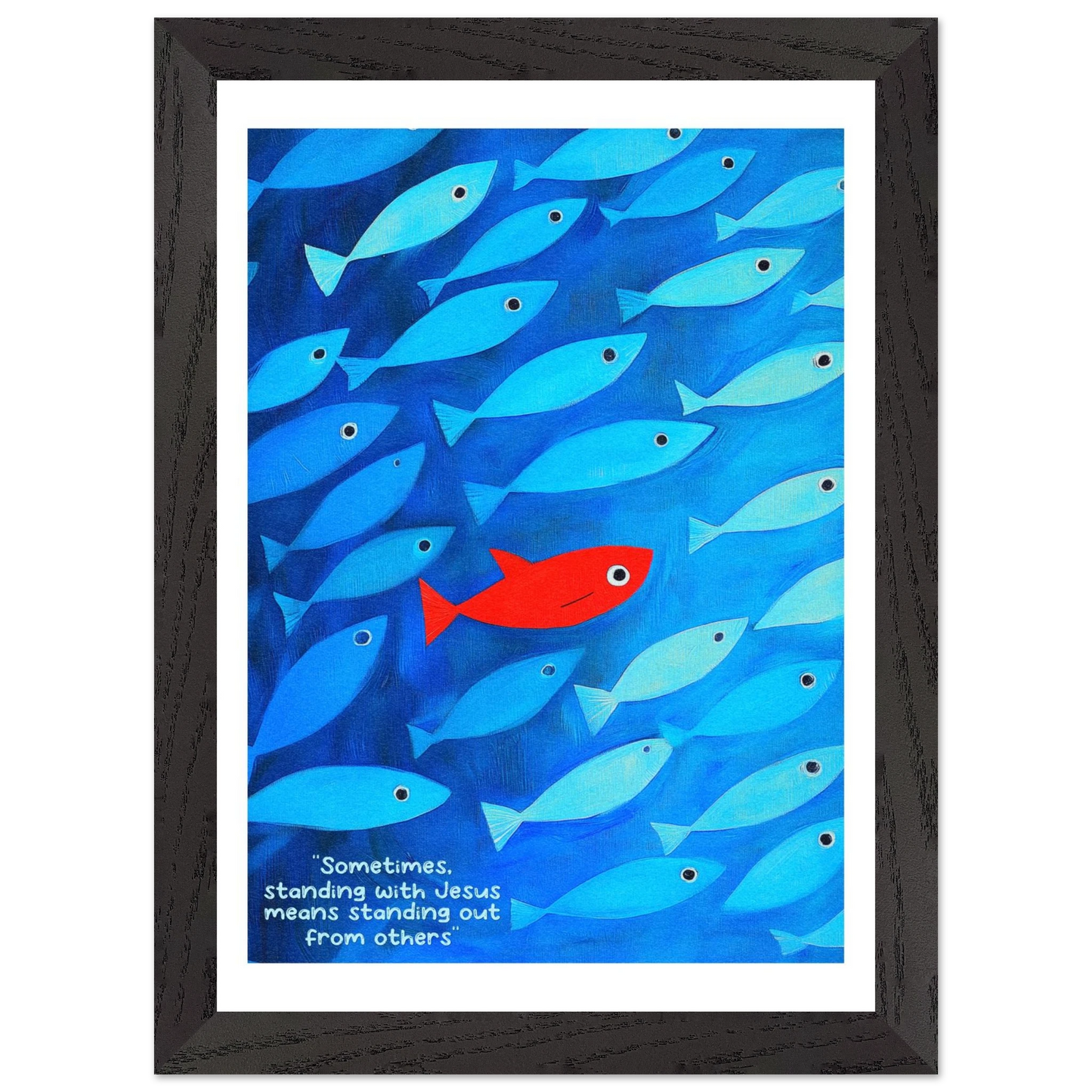 Framed wall art featuring a school of blue fish with a single red fish, and text that reads: 'Sometimes standing with Jesus means standing out from others.'.