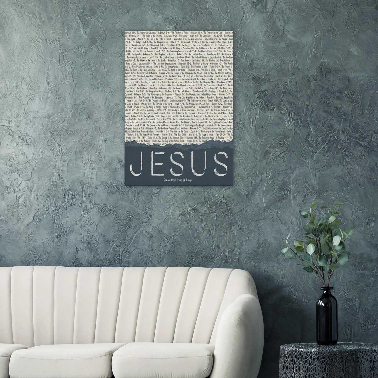 Wall art with 'Jesus' text on a textured gray wall above a white sofa.