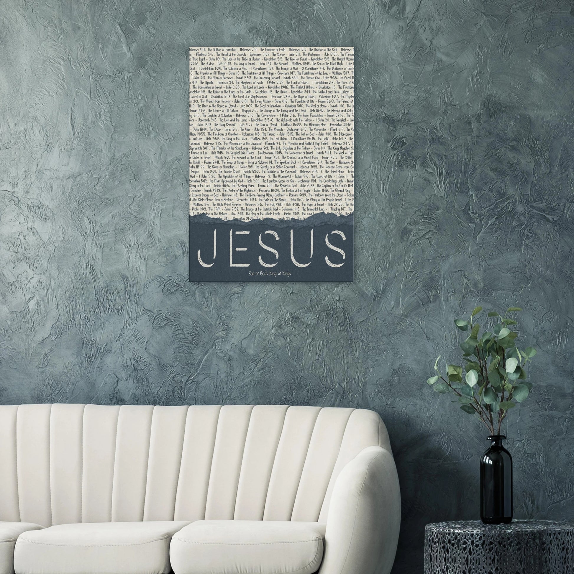 Wall art with 'Jesus' text on a textured gray wall above a white sofa.