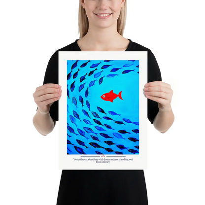 Person holding a framed artwork with blue fish and a red fish on a white background