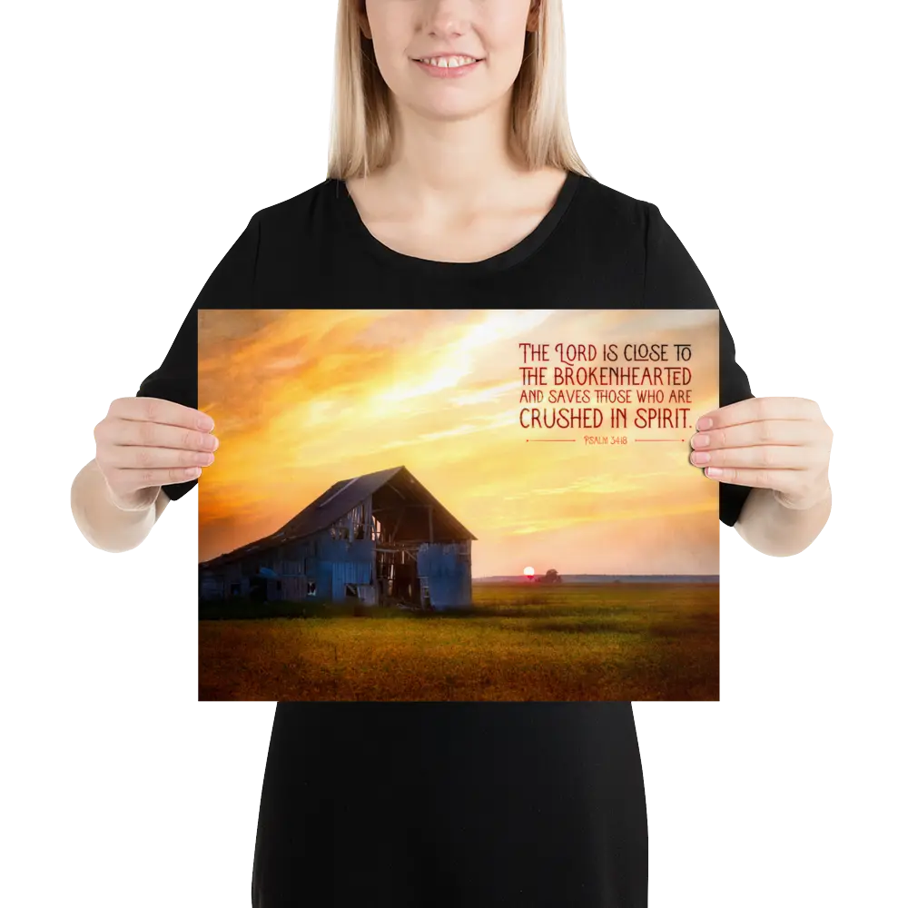 Person holding a poster with a sunset over a barn and inspirational text.