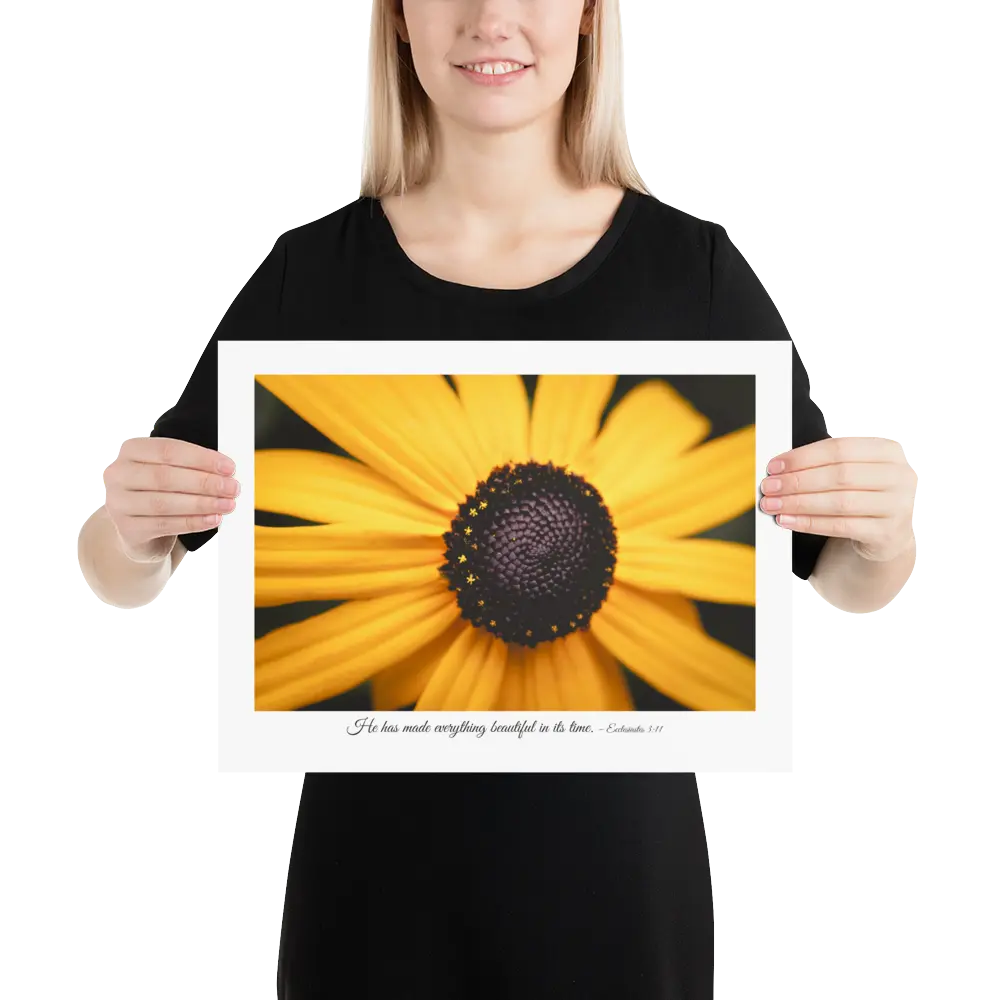 Person holding a framed print of a yellow flower with a black center.