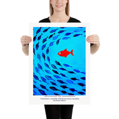 Person holding a poster with a red fish among blue fish and text on a white background