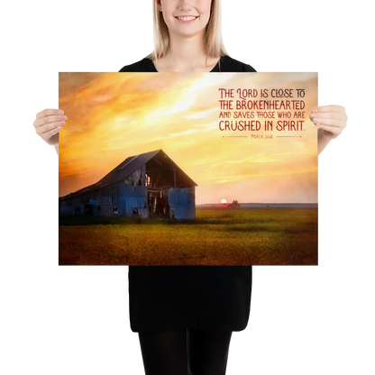 Person holding a poster with a barn and sunset scene and inspirational text.