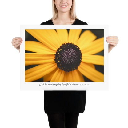 Person holding a large print of a yellow flower with a black center.