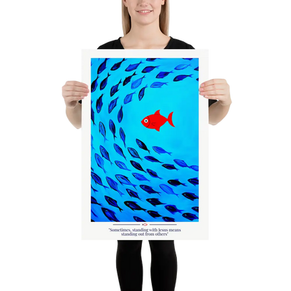 Person holding a poster with a red fish among blue fish on a blue background.