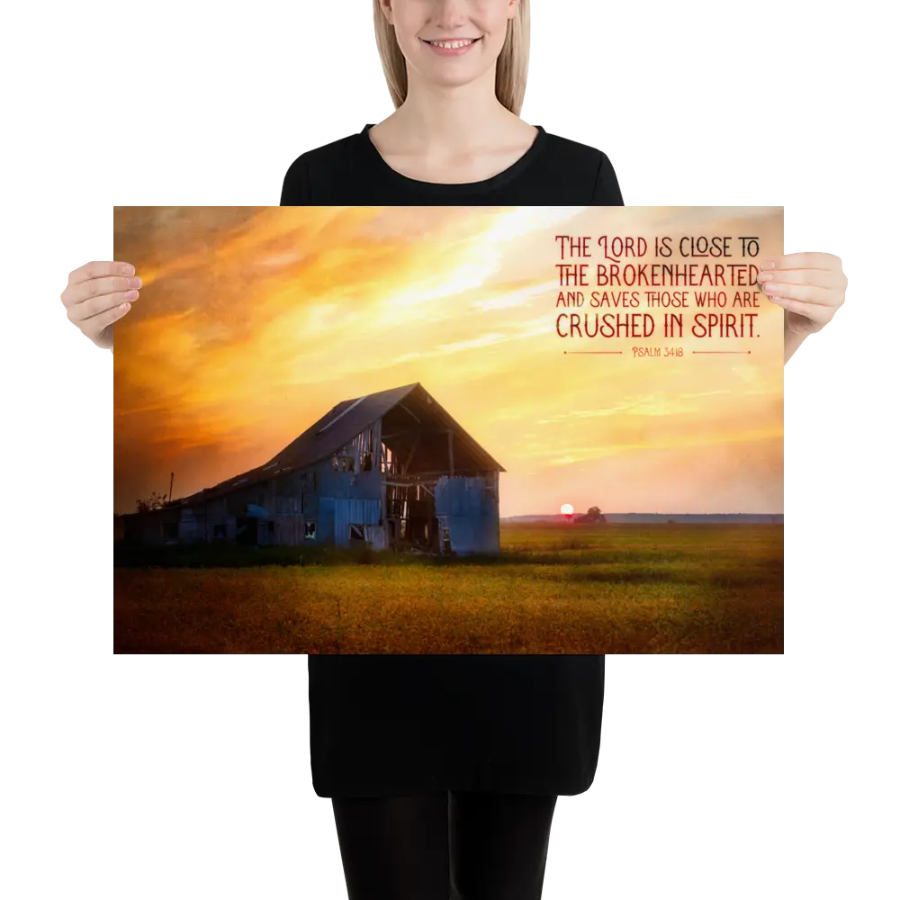 Person holding a poster with a sunset over a barn and Bible verse text.